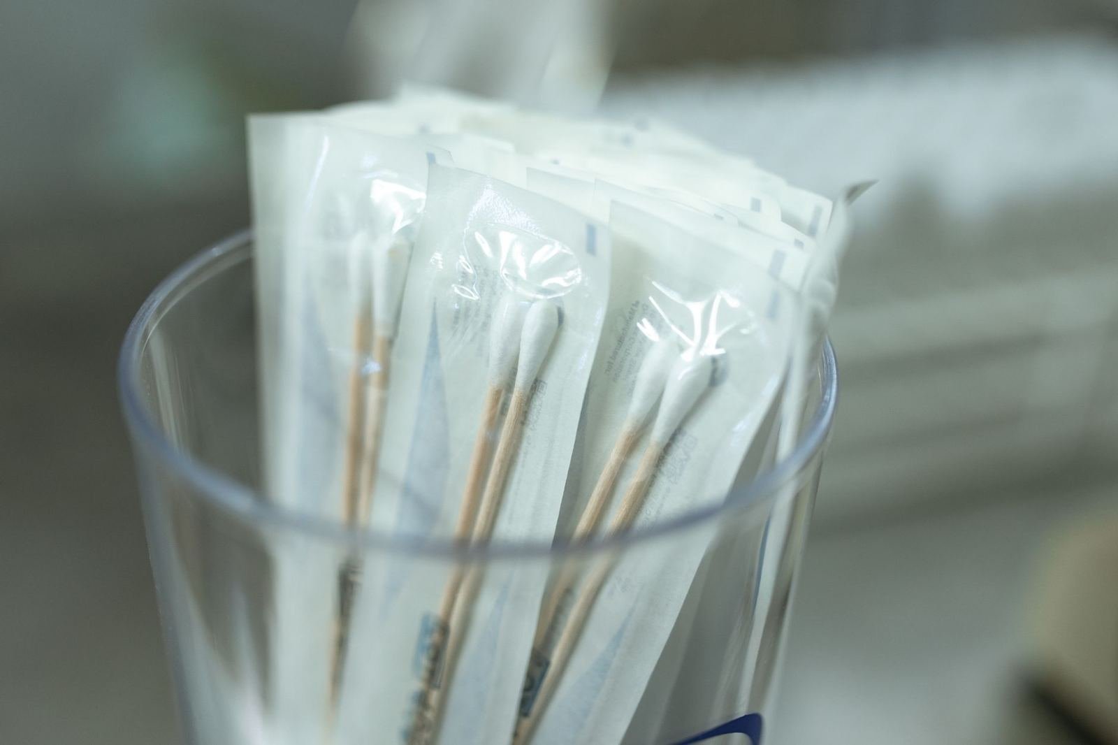 Hisopos estériles empacados individualmente dentro de un vaso transparente, sin personas ni texto legible