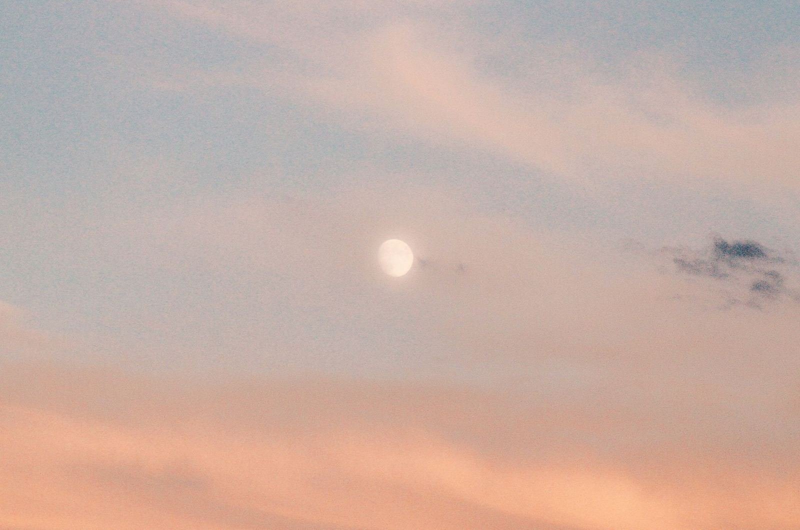 Luna tenue entre nubes rosadas y azules al amanecer, imagen abstracta sin personas ni texto