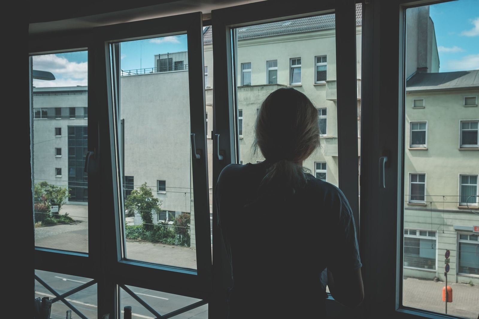Mujer de espaldas mirando por la ventana de su casa, en un momento de calma