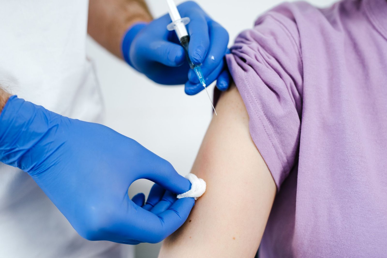 Primer plano de un profesional de la salud aplicando una vacuna en el brazo de un paciente, en una clínica moderna