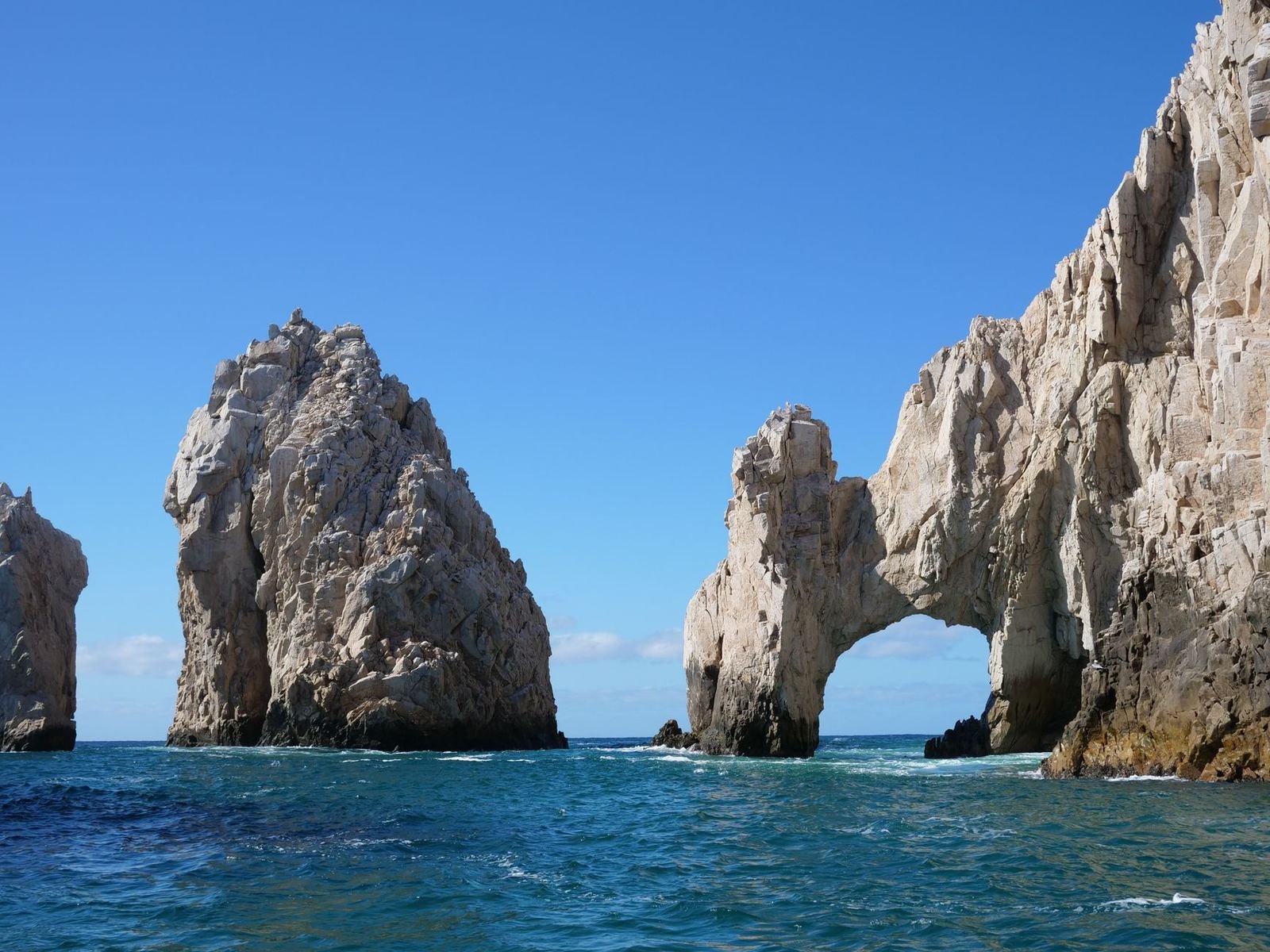 Formaciones rocosas con un arco natural que se adentran en el mar azul bajo un cielo despejado, en Cabo San Lucas, sin personas