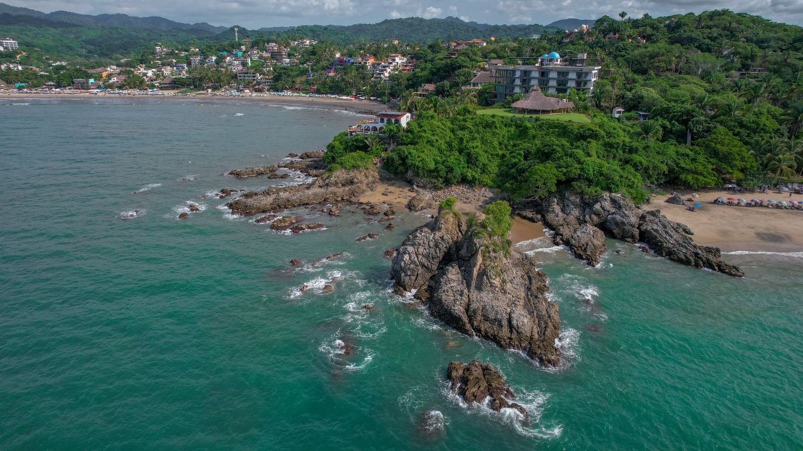 Vista aérea de una costa rocosa del Pacífico con vegetación tropical y aguas turquesa, sin personas