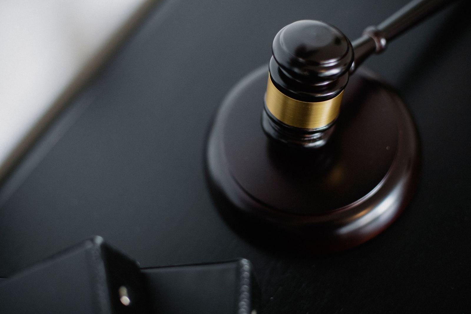 Mazo de madera con anillo dorado sobre su base, en un escritorio oscuro, sin personas ni texto