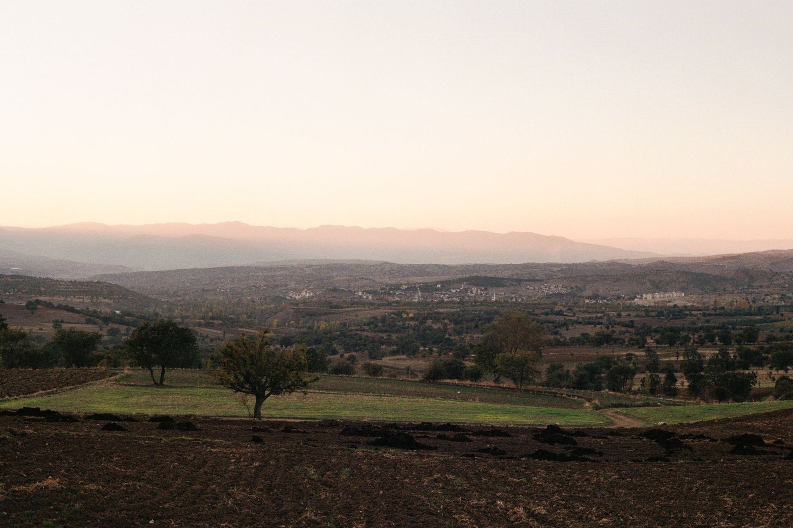 Vista panorámica de un valle con colinas y montañas al atardecer, sin personas
