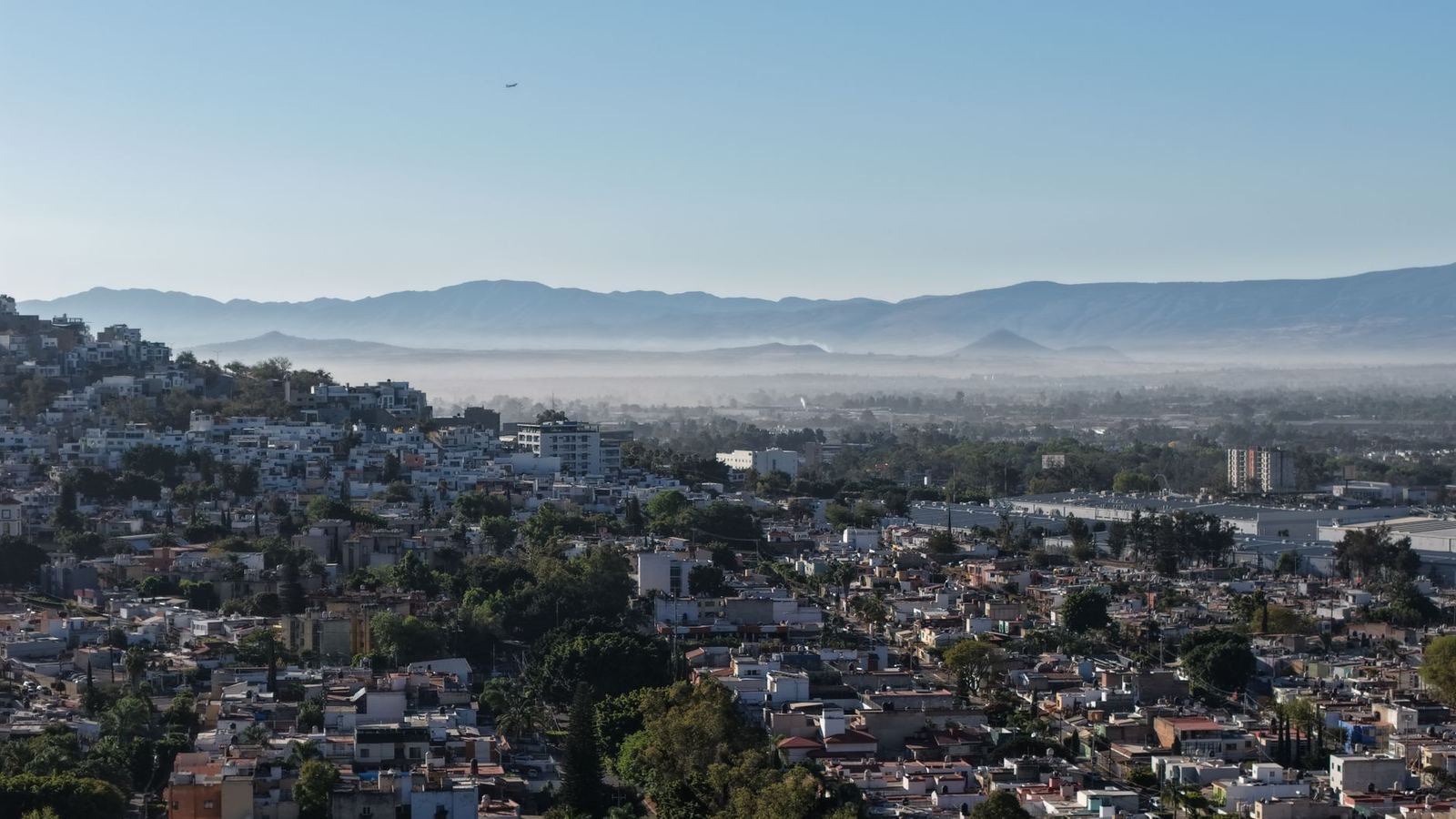 Vista aérea de una zona urbana con cerros al fondo por la mañana, sin personas