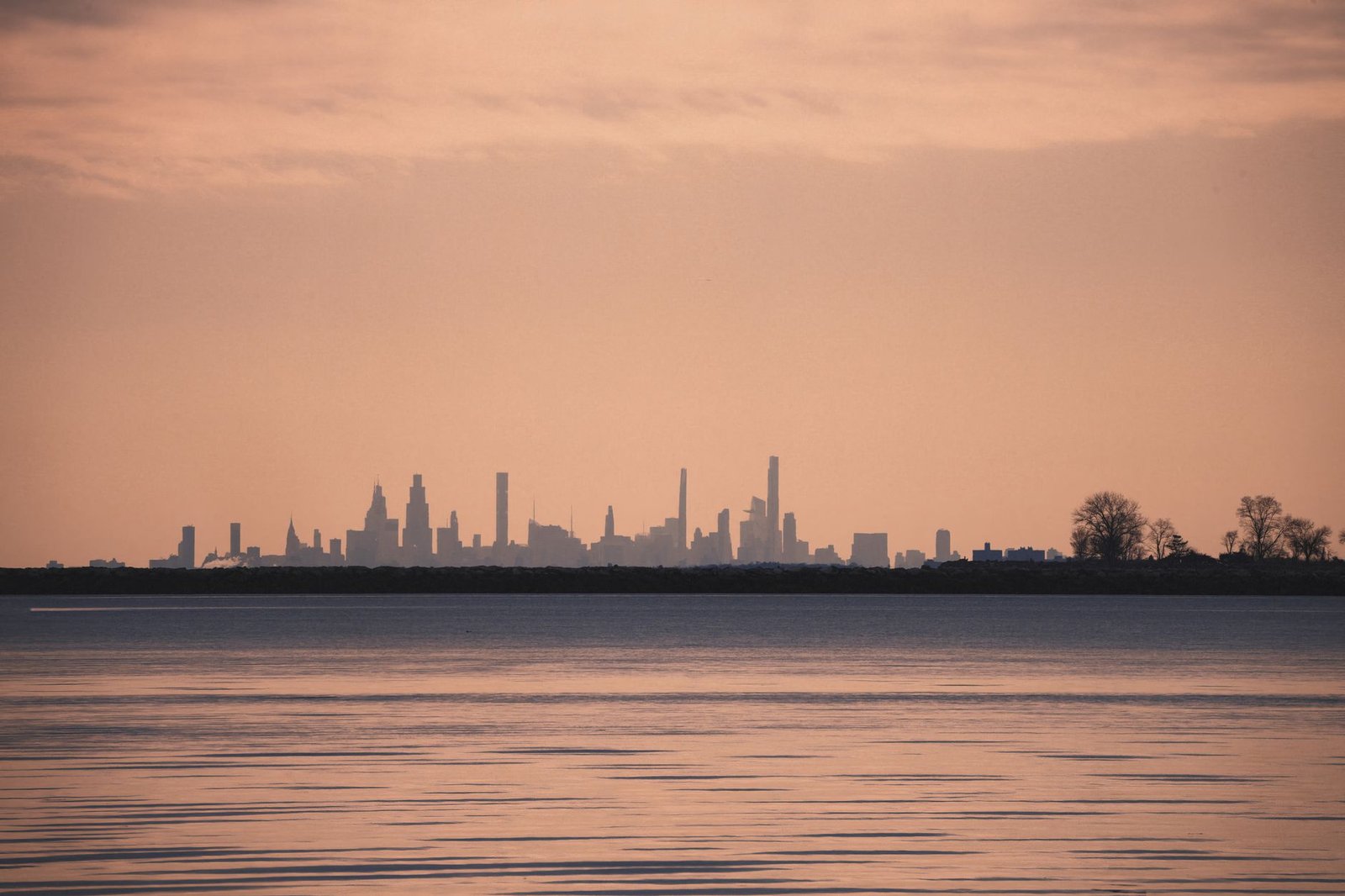Silueta del horizonte de una ciudad al atardecer, vista desde el otro lado del agua, sin personas