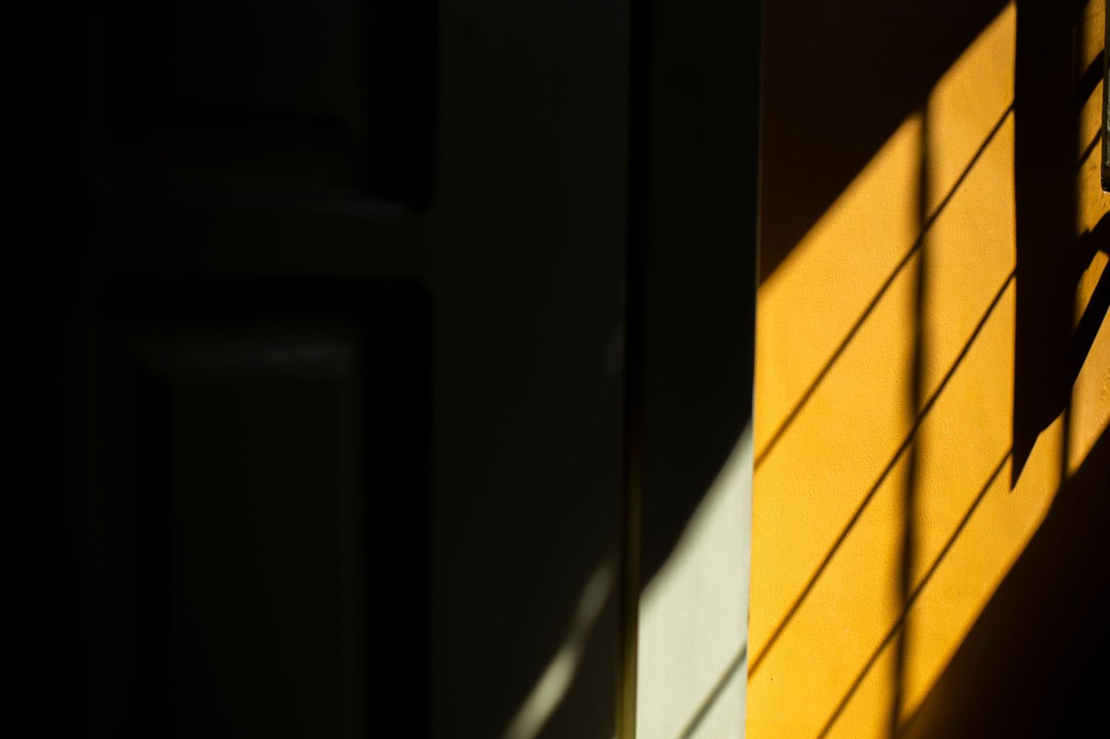 Contraste de luz y sombra en diagonal sobre una pared amarilla, sin personas