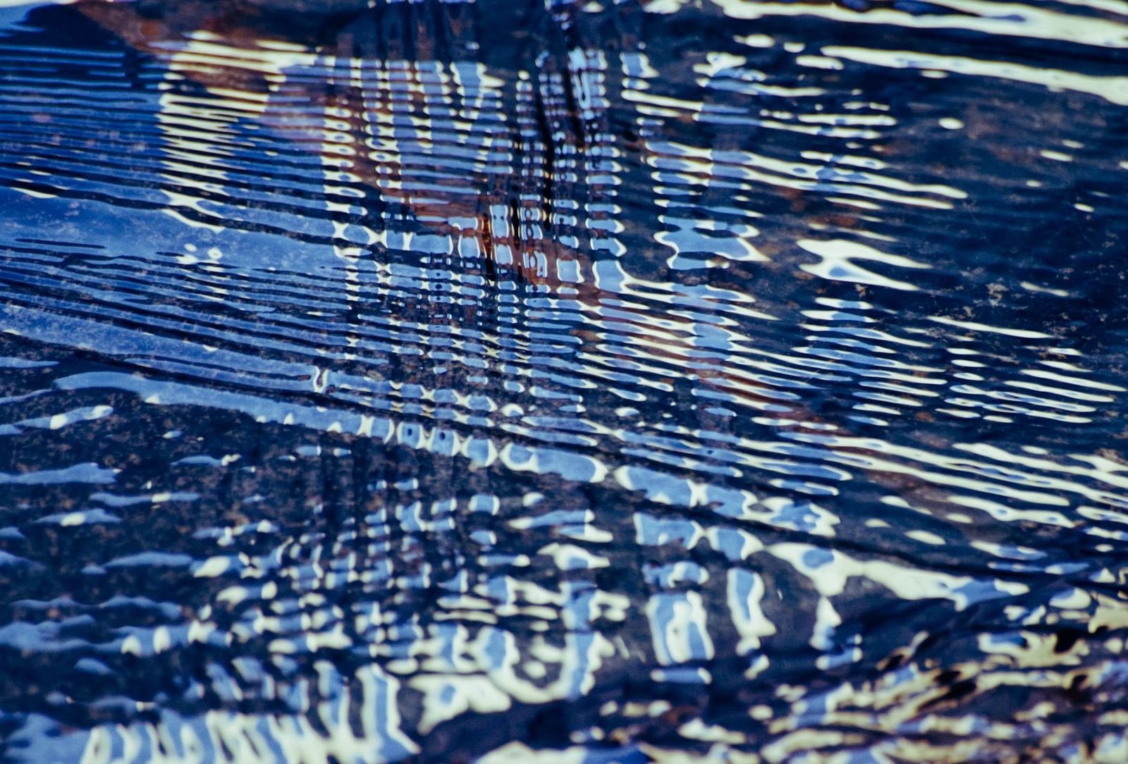 Reflejos y ondas azules sobre la superficie del agua, imagen abstracta sin personas ni texto